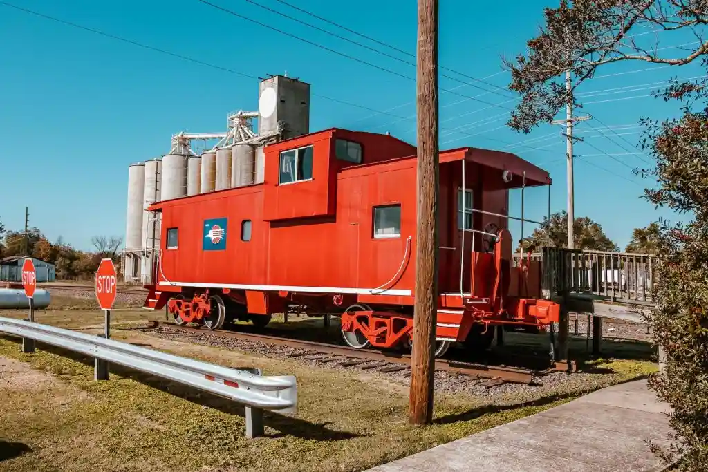 A restored red caboose displayed next to grain elevators at the Dexter Welcome Center Depot and Museum.