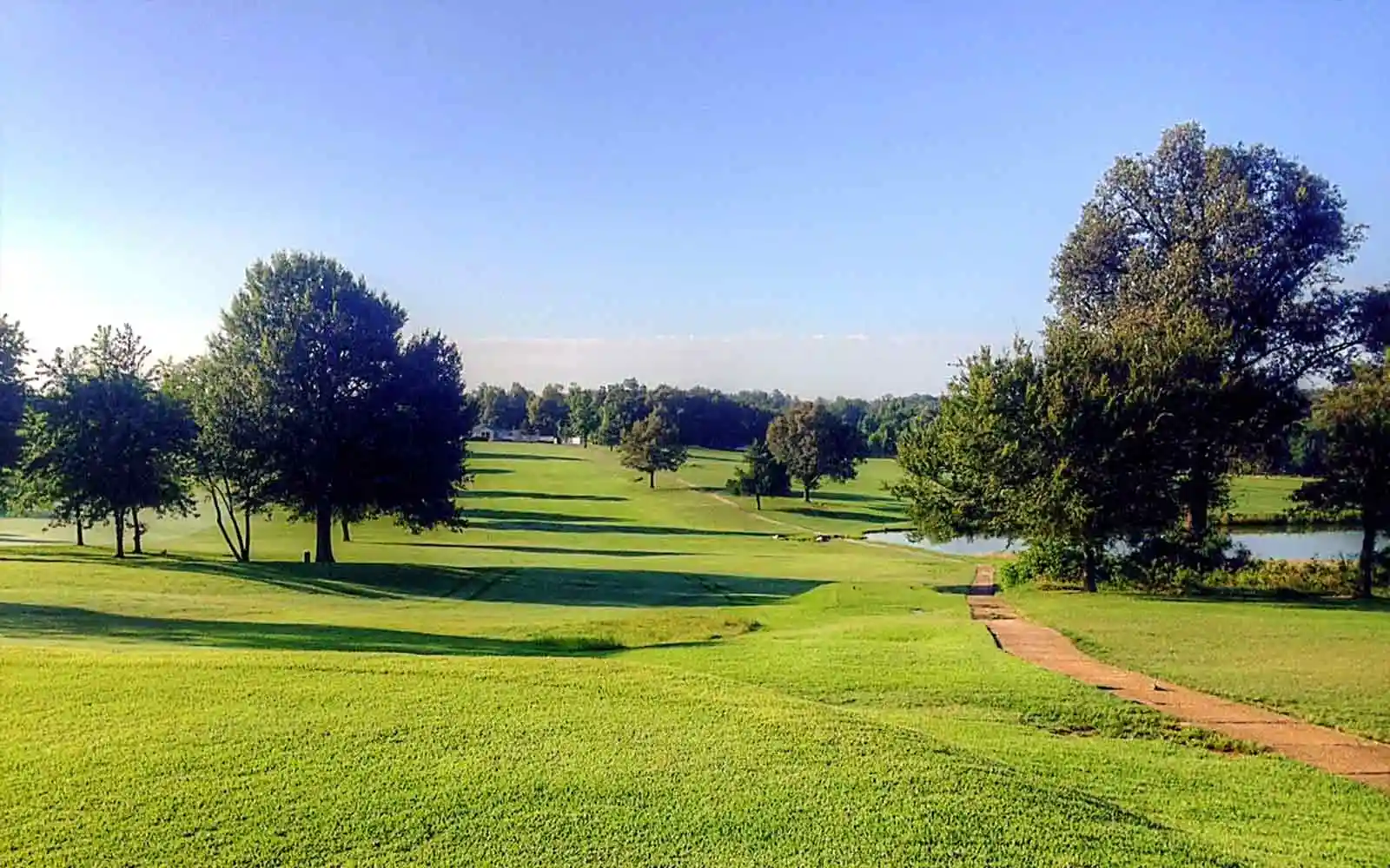 A golf course fairway lined with trees and a pond at Hidden Trails Country Club near Dexter.